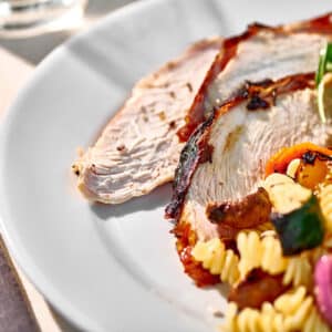 Slices of grilled turkey breast on plate with salads.