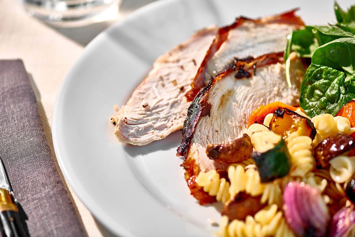 Slices of grilled turkey breast on plate with salads.