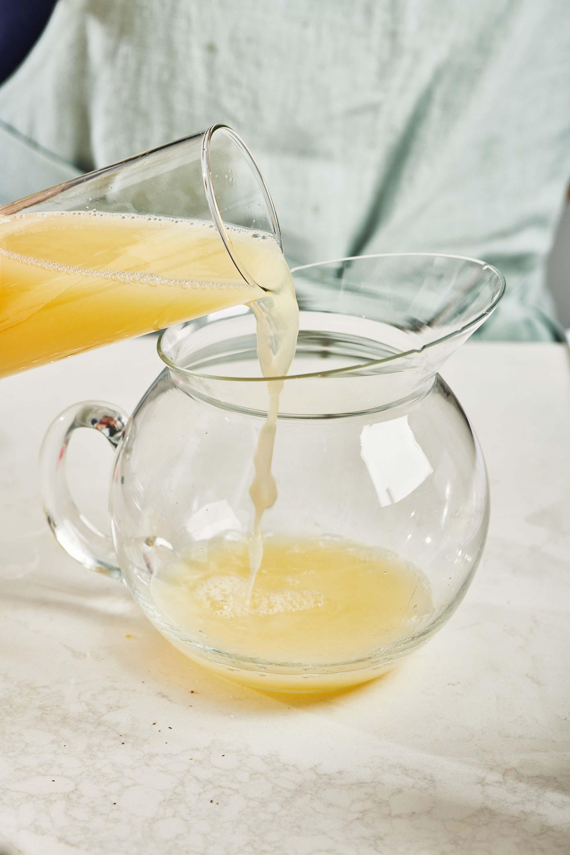 Fresh lemon juice pouring into a glass pitcher.