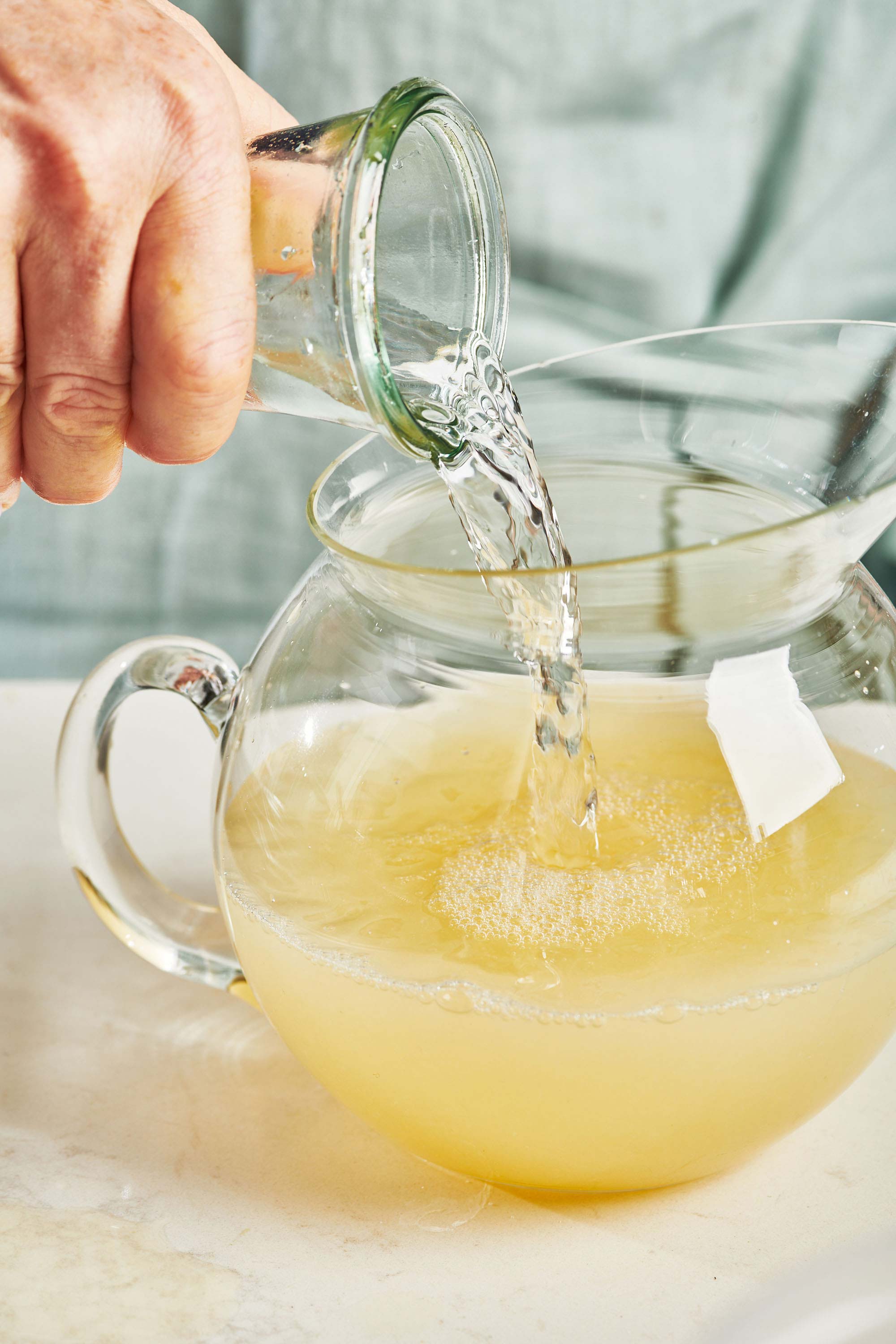 Glass jar of cold water pouring into a pitcher.