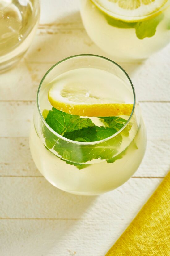 Small glass of Lemonade with lemon slices and mint leaves.