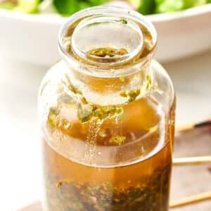 Glass jar of Chermoula next to skewered meat.