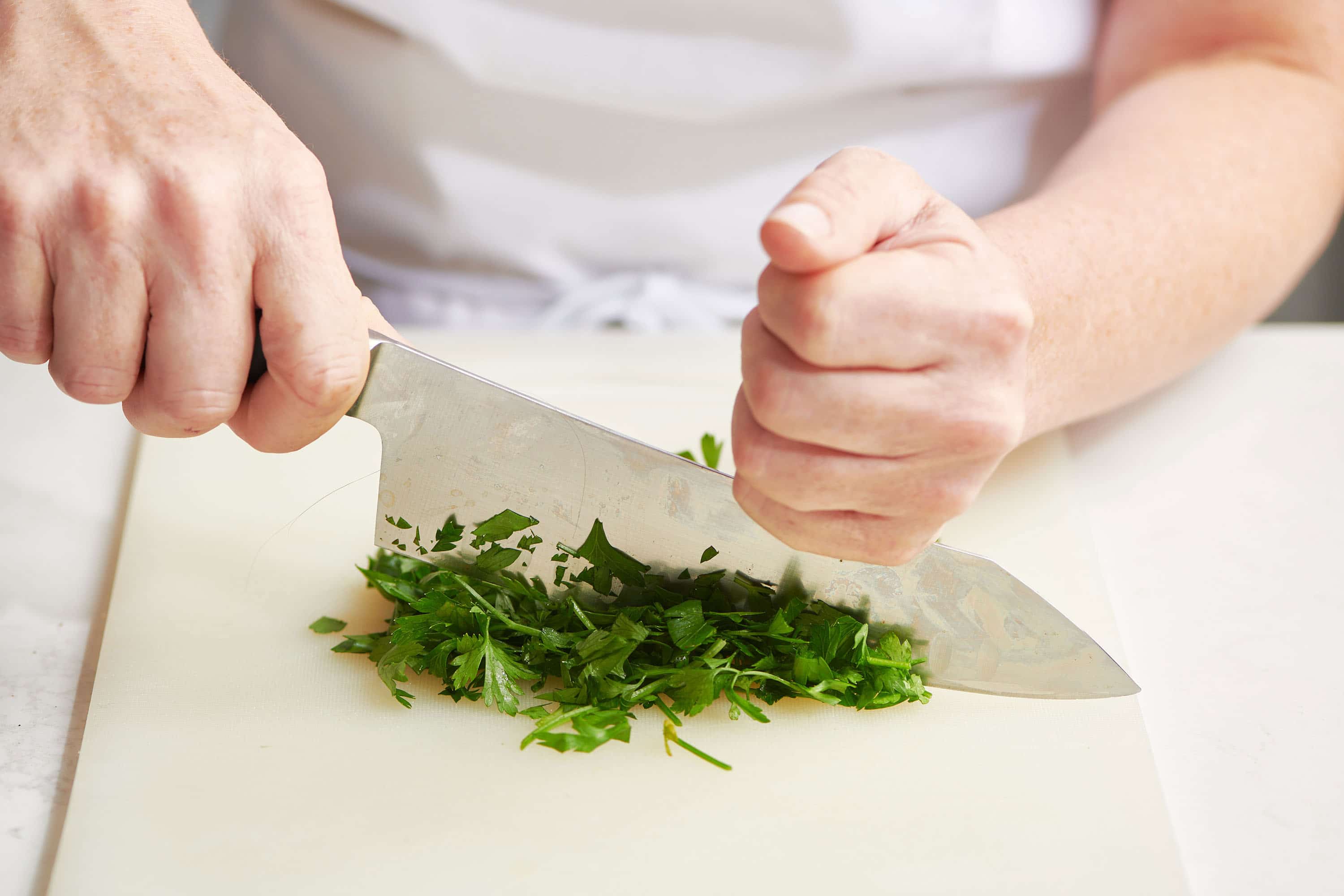 Chopping parsley with chef knife.