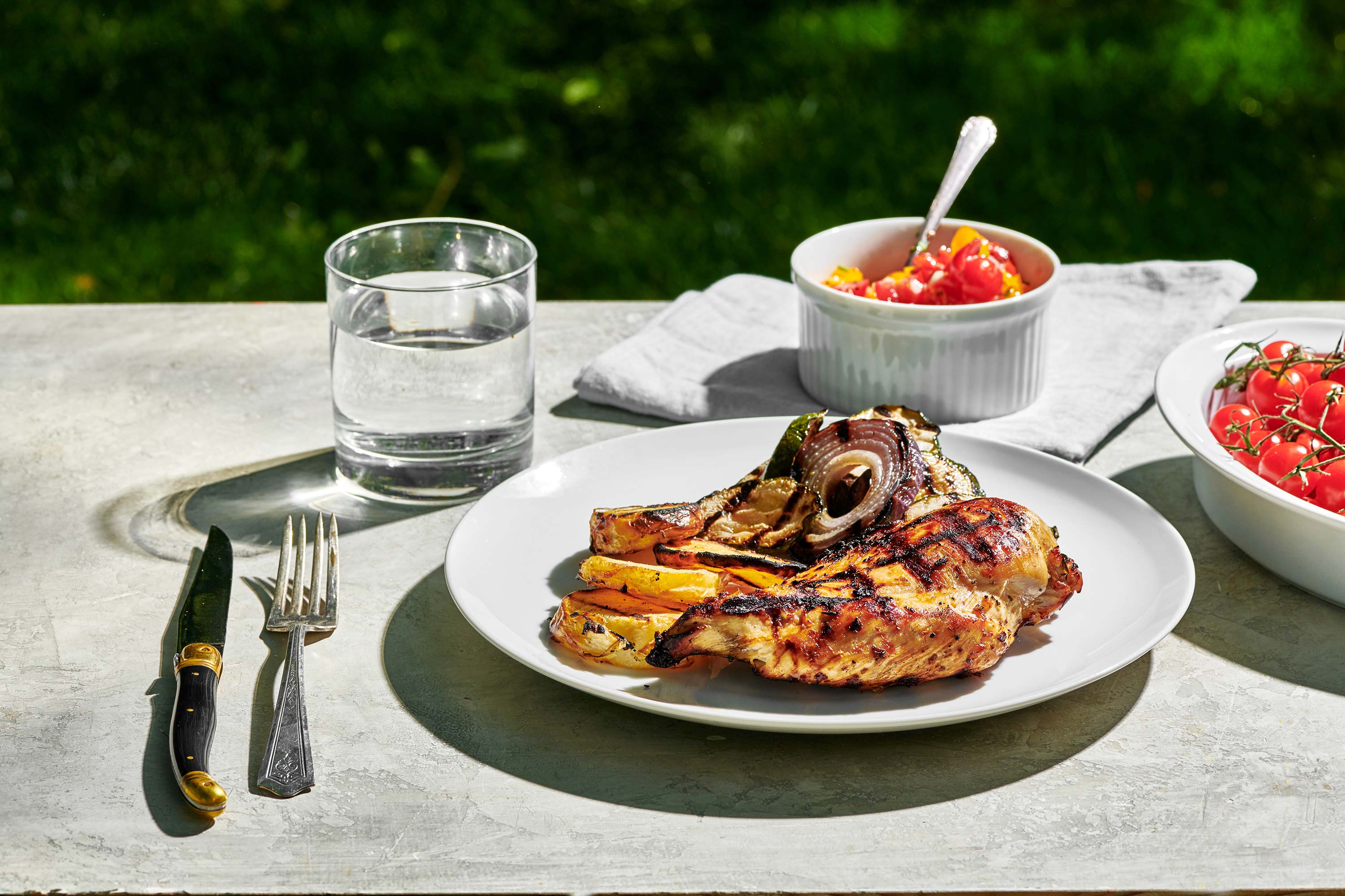 Grilled Chicken Breast and vegetables on a plate on an outdoor table.