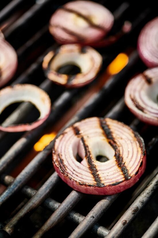 Sliced red onions on a grill.