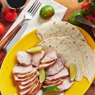 Plate set with tortillas and slices of grilled pork.