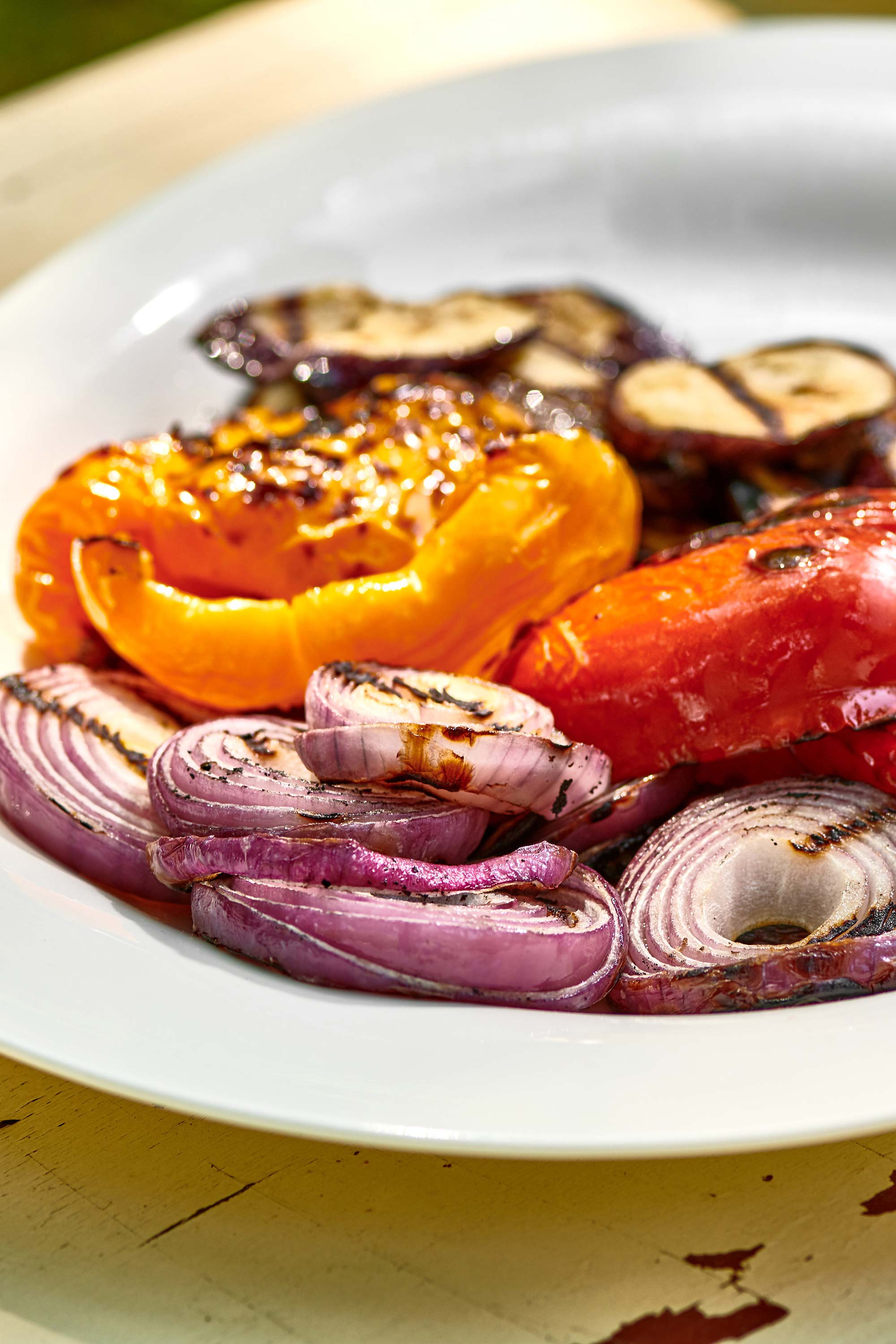 Grilled red onions, bell peppers, and eggplant on a platter.