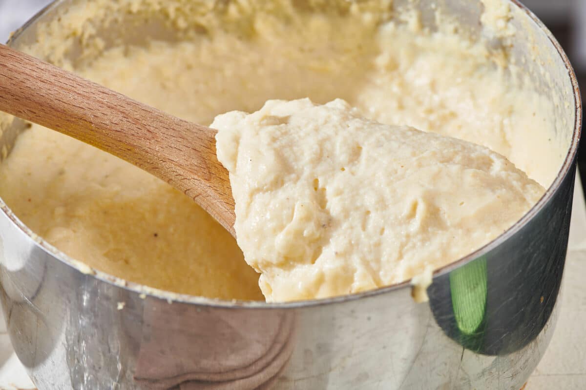 Wooden spoon in a pot of creamy polenta.