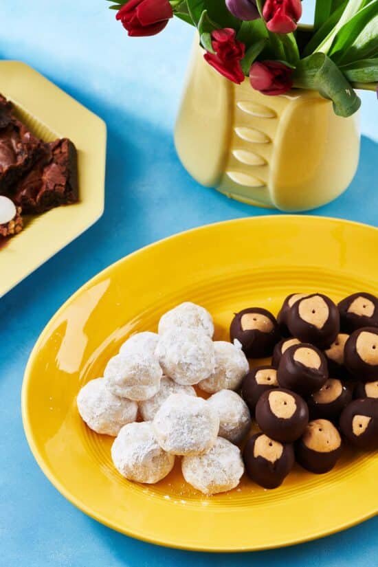 Yellow platter of Nut-Free Snowball Cookies and buckeye balls.