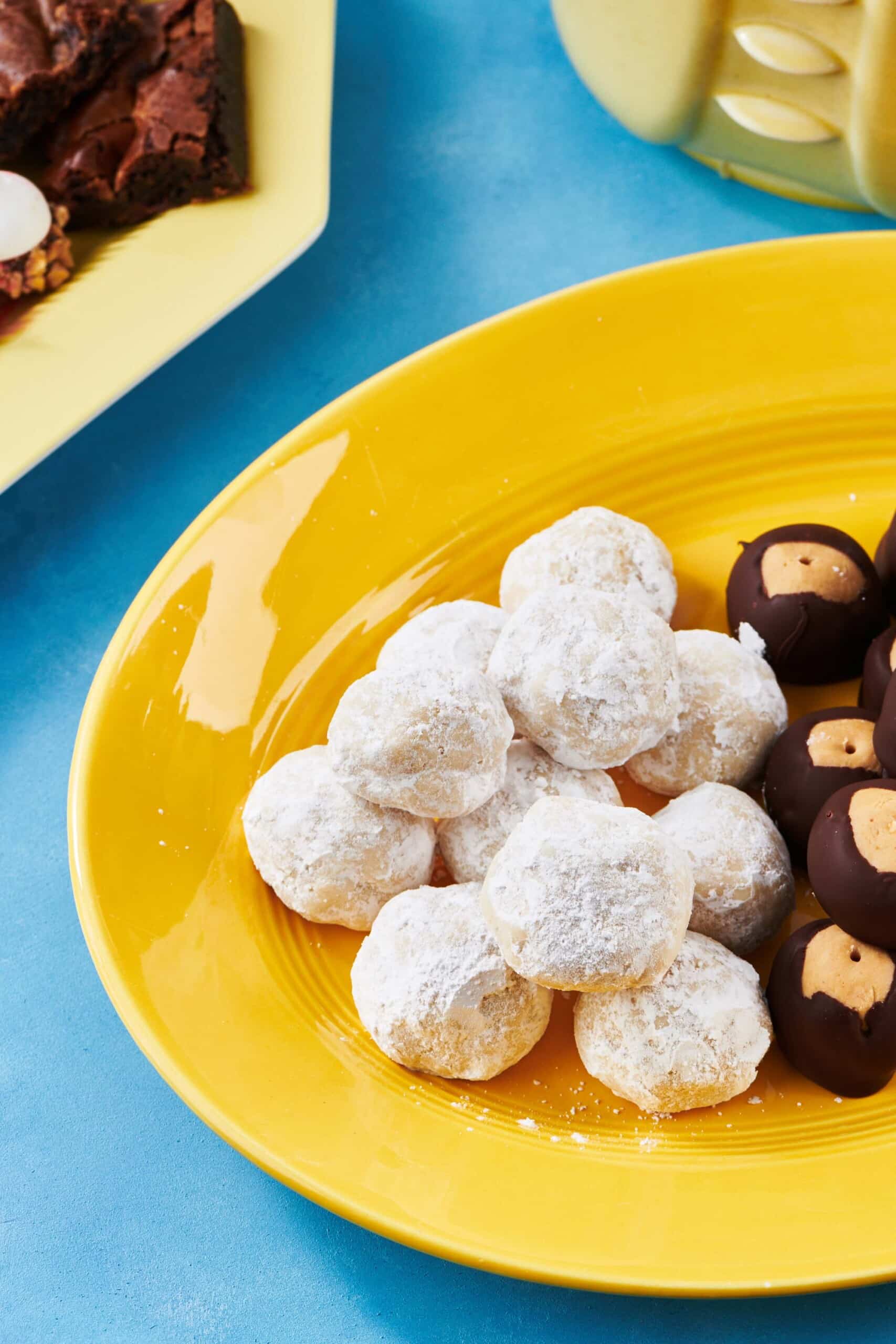 Nut-Free Snowball Cookies with Buckeyes on a yellow dish.