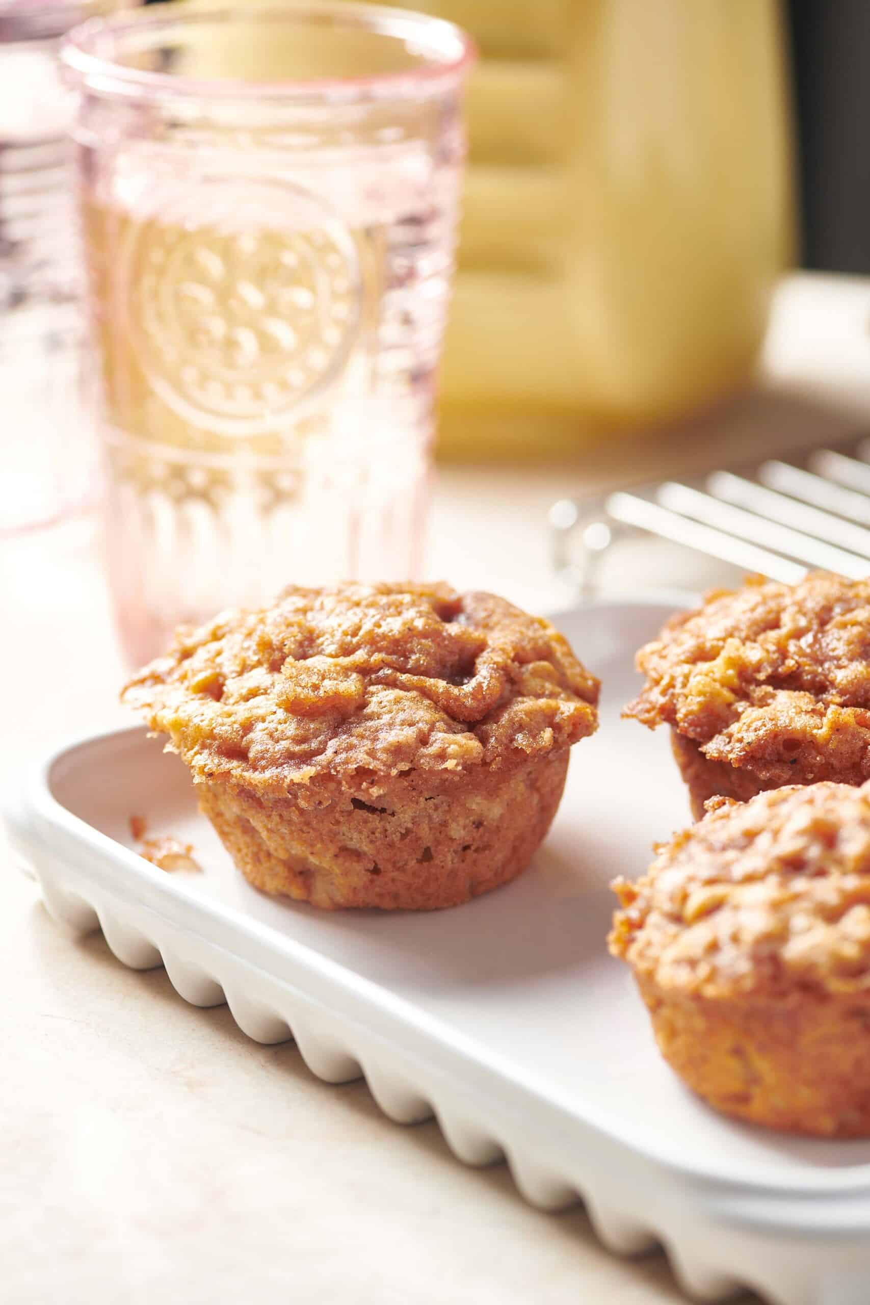 Brown Butter Apple Streusel Muffins on serving platter next to water glass.