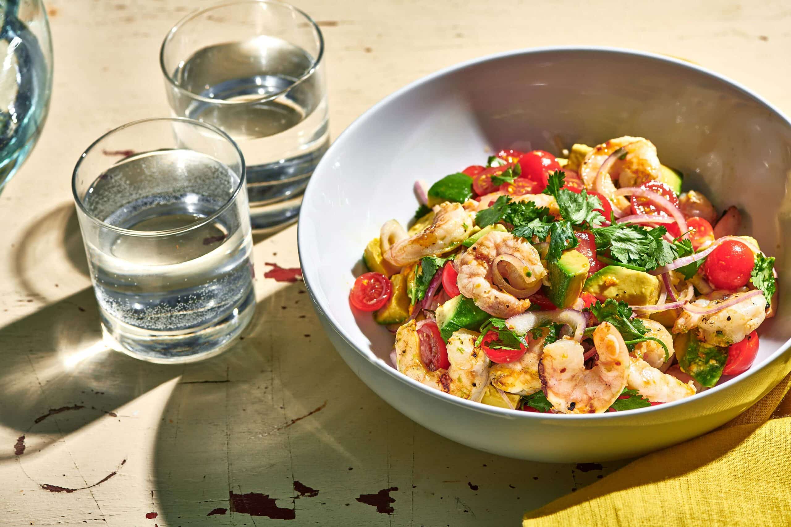 Large bowl of Grilled Shrimp Salad with Citrus Dressing on table with glasses of water.
