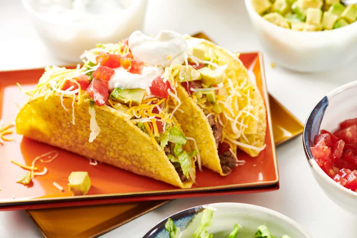 Ground Beef Tacos topped with avocadoes, cheese, and sour cream.
