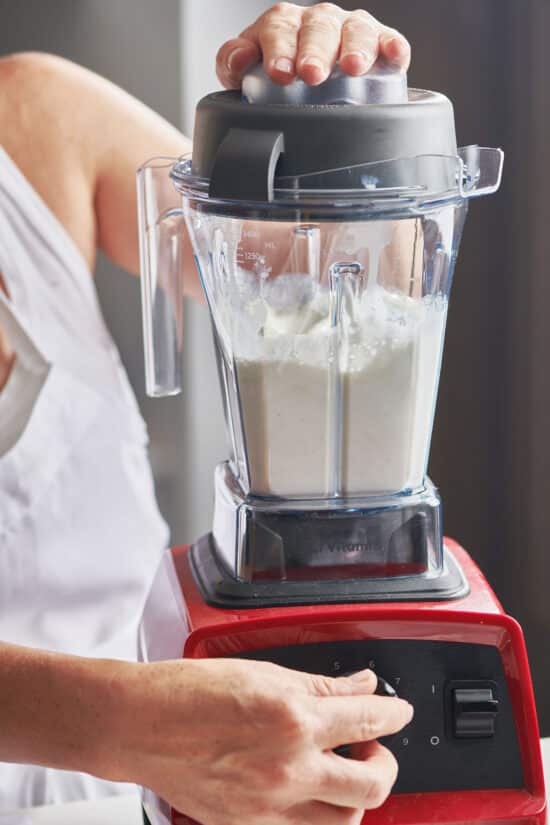 Woman turning on a blender of Vanilla Milkshake ingredients.