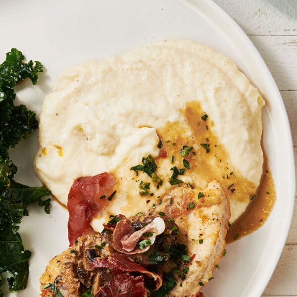 Creamy Polenta on a plate with greens and chicken.
