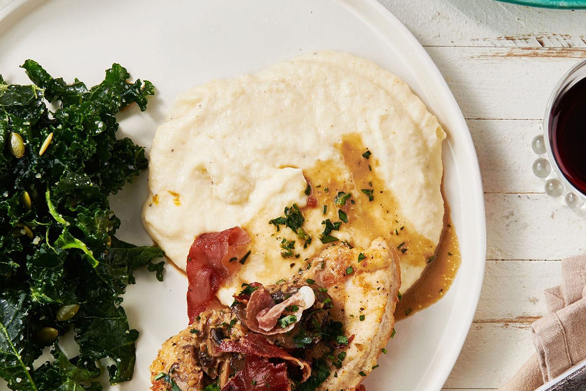Creamy Polenta on a plate with greens and chicken.