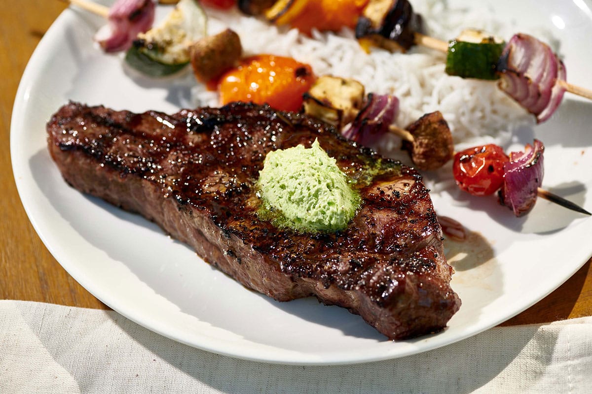 New York Strip Steak with compound jalapeno butter on plate.
