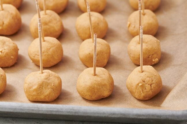Buckeye Ball with toothpicks on a lined baking sheet.