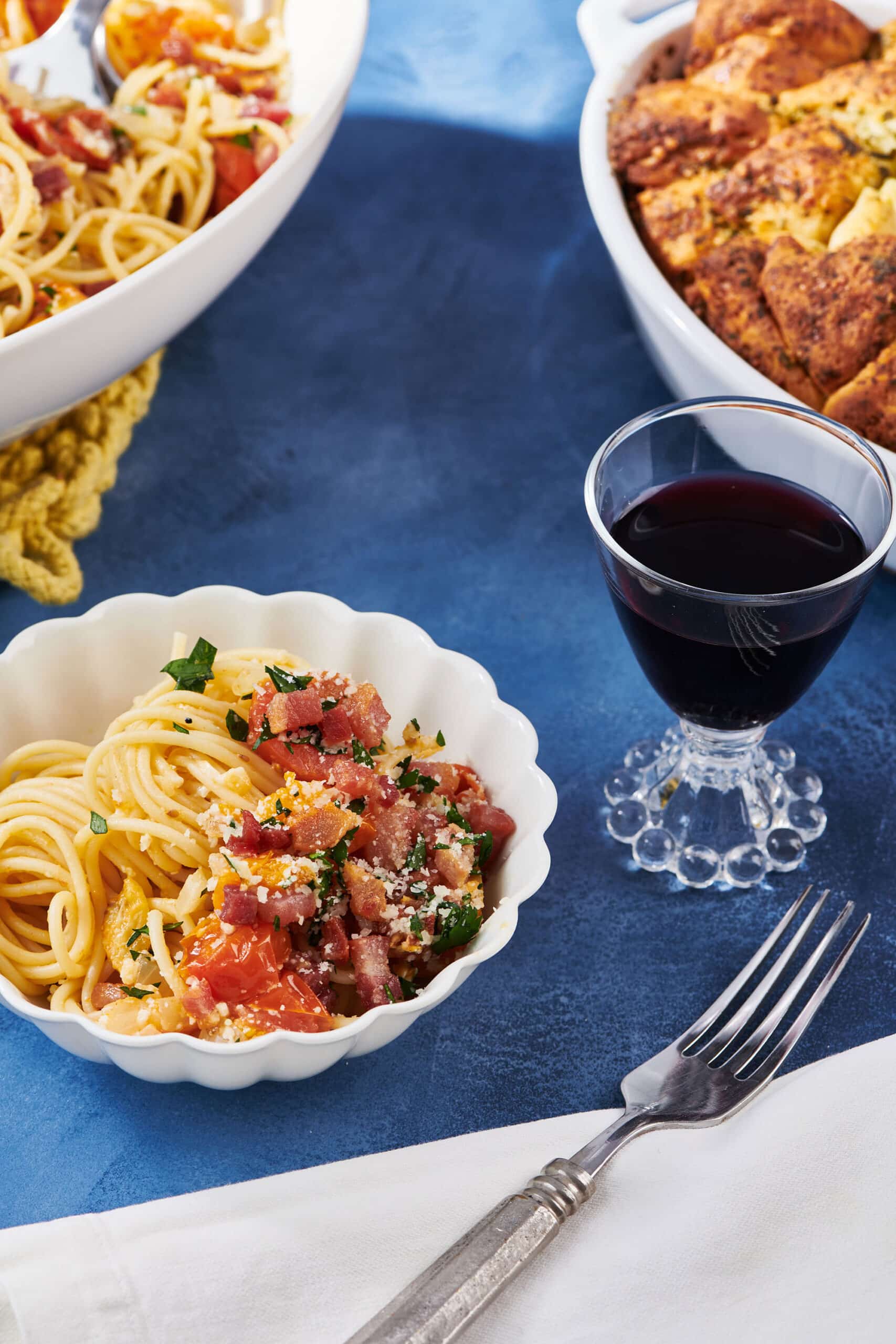 Pancetta Pasta with Tomatoes in serving bowls with glass red wine.