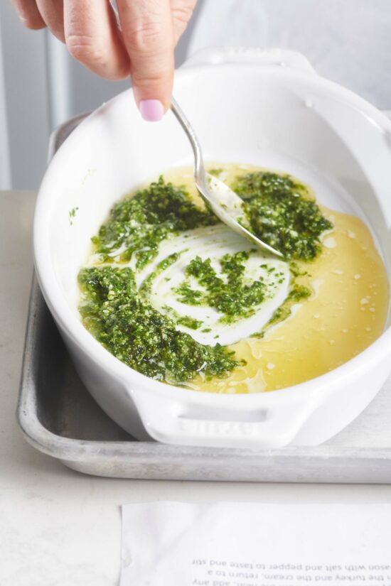 Woman stirring pesto and butter together.
