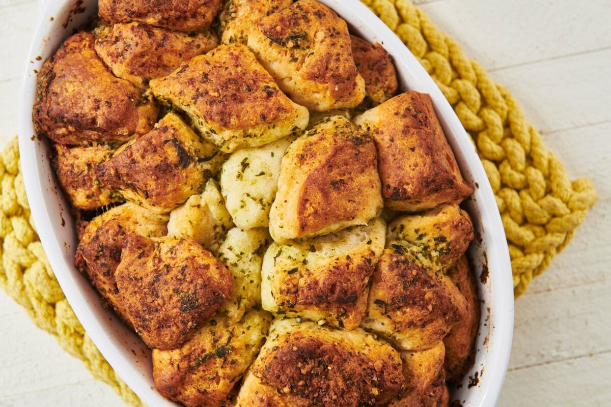 Pesto Monkey Bread in a white dish on a yellow trivet.