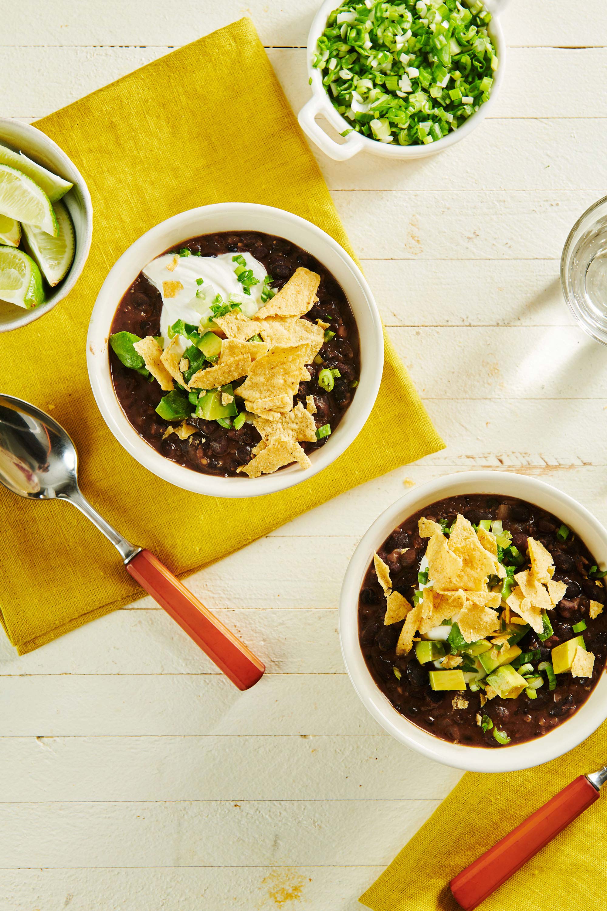 Two bowls of Vegetarian Black Bean Soup with toppings.