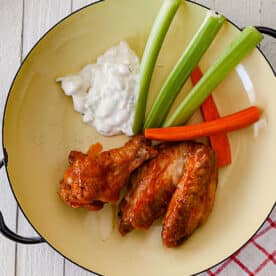 Air-fried Buffalo chicken wings on plate with celery, carrots, and blue cheese dip.
