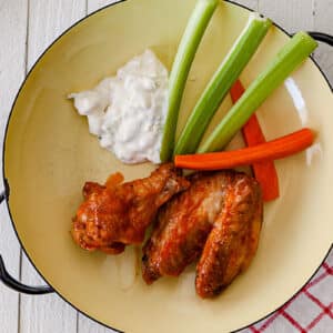 Air-fried Buffalo chicken wings on plate with celery, carrots, and blue cheese dip.