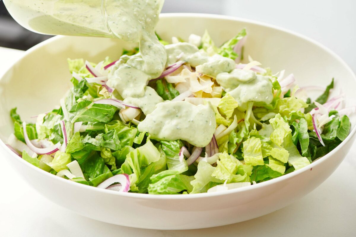 Avocado Ranch Dressing being poured on a bowl of salad.
