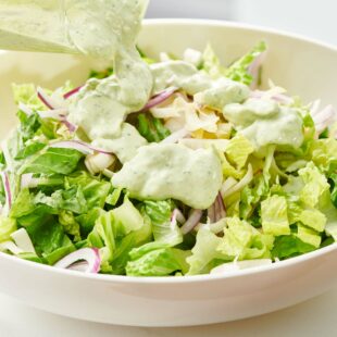 Avocado Ranch Dressing being poured on a bowl of salad.
