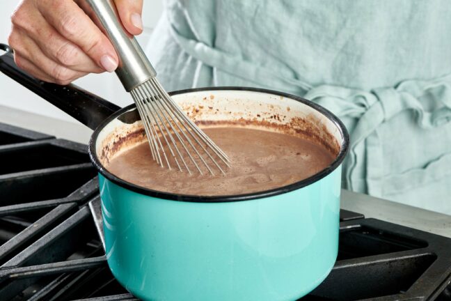 Woman whisking a small pot of Homemade Hot Chocolate.