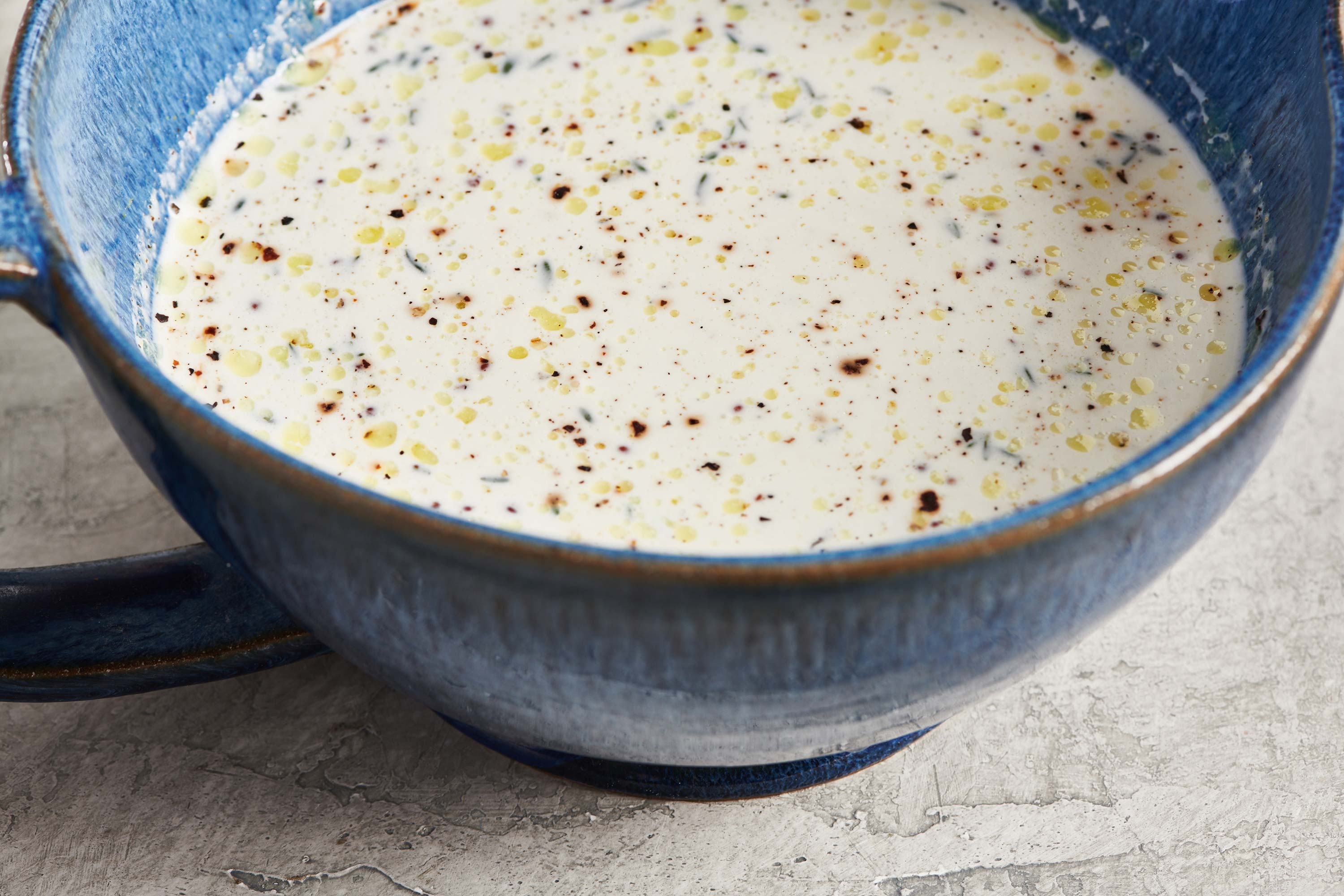 Speckled broth and cream mixture in a blue bowl.