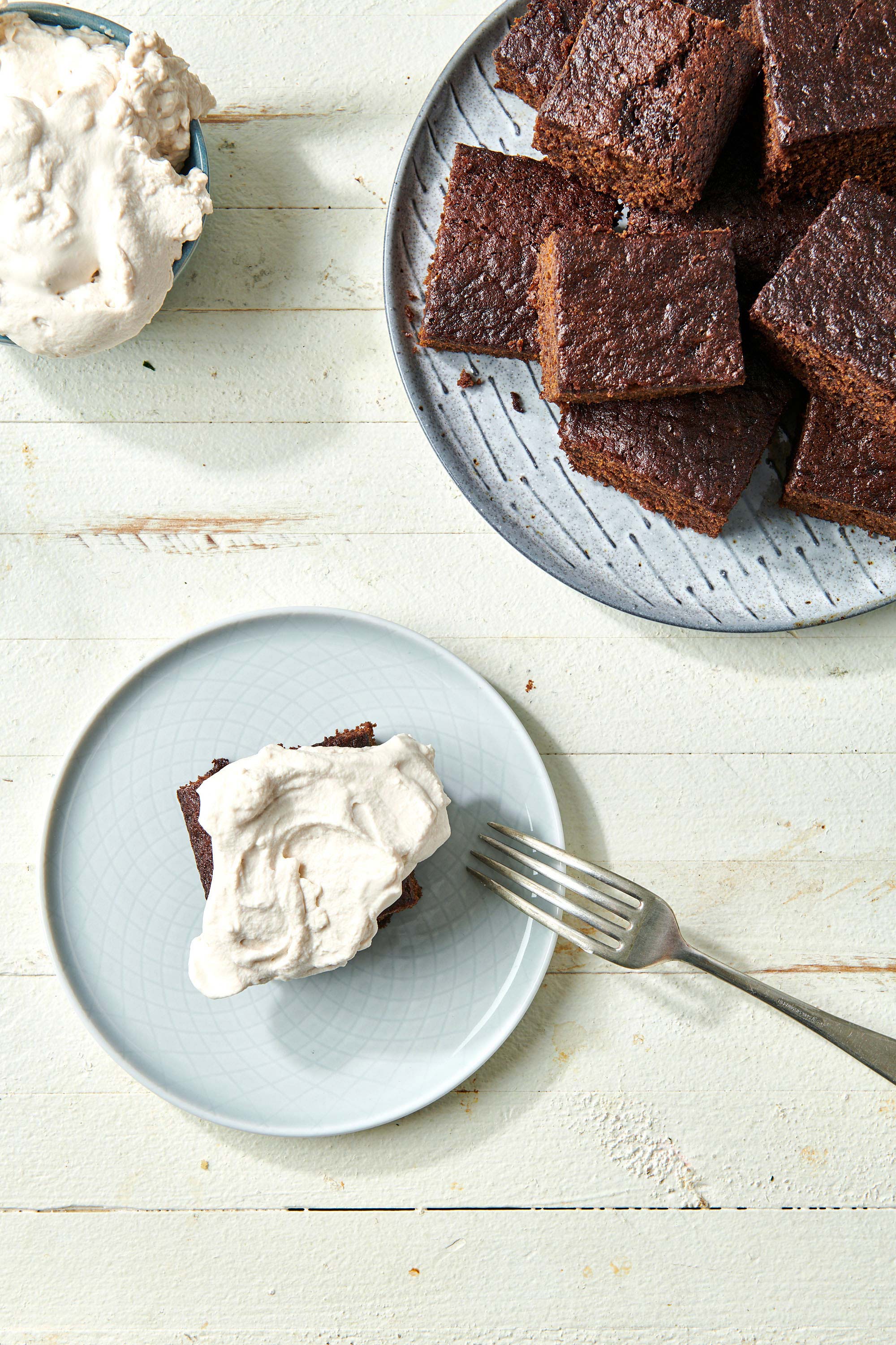 Piece of Gingerbread Cake on a plate with whipped cream and a fork.
