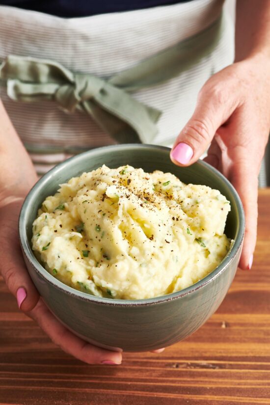 Woman holding a bowl of herb mashed potatoes.