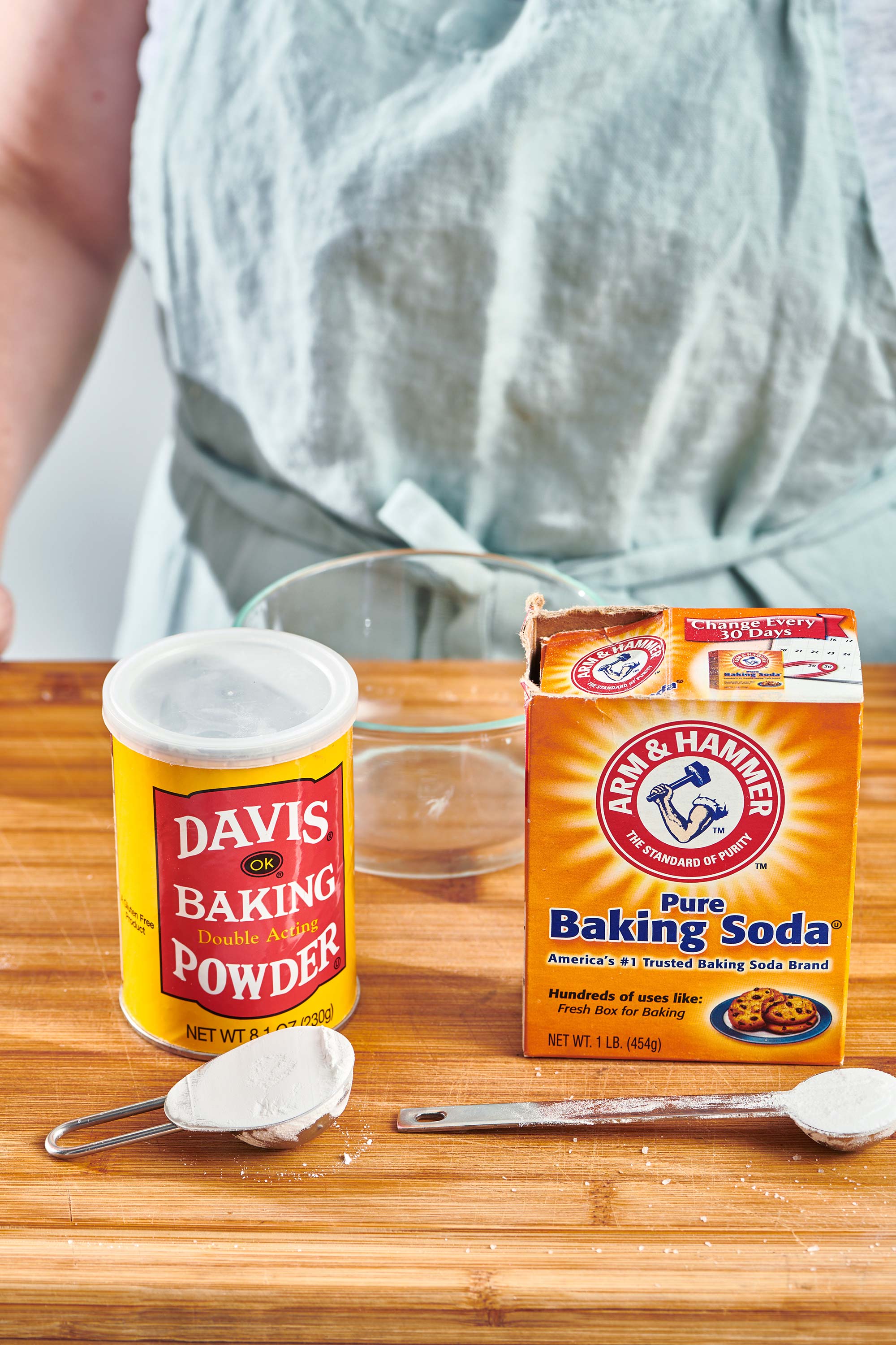 Woman standing behind packages of baking powder and baking soda on a counter.