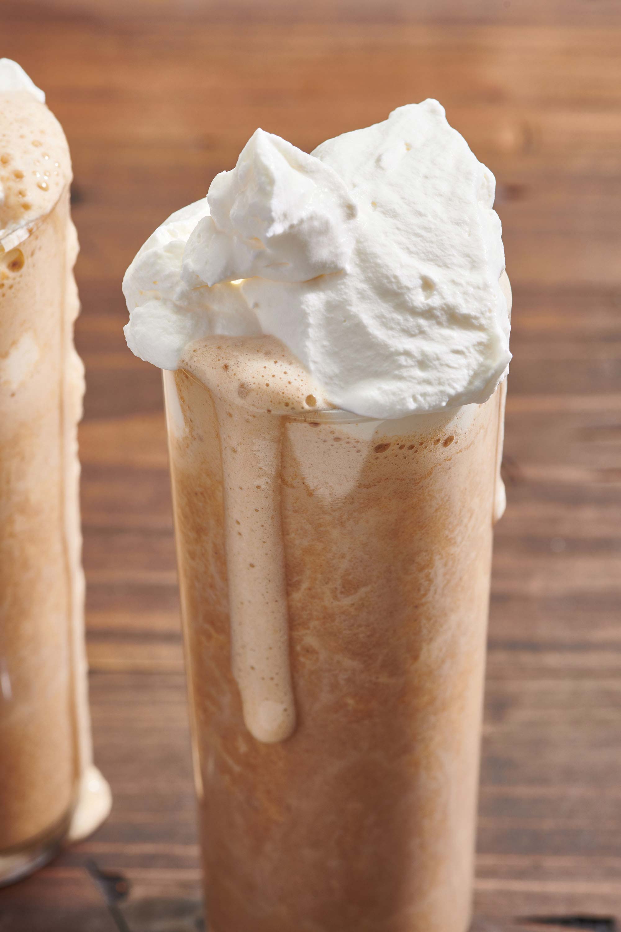 Iced Pumpkin Spice Latte topped with whipped cream dripping down the side of a glass.