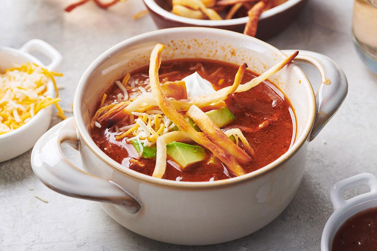 Mexican Tortilla Chicken Soup in white bowl on table.