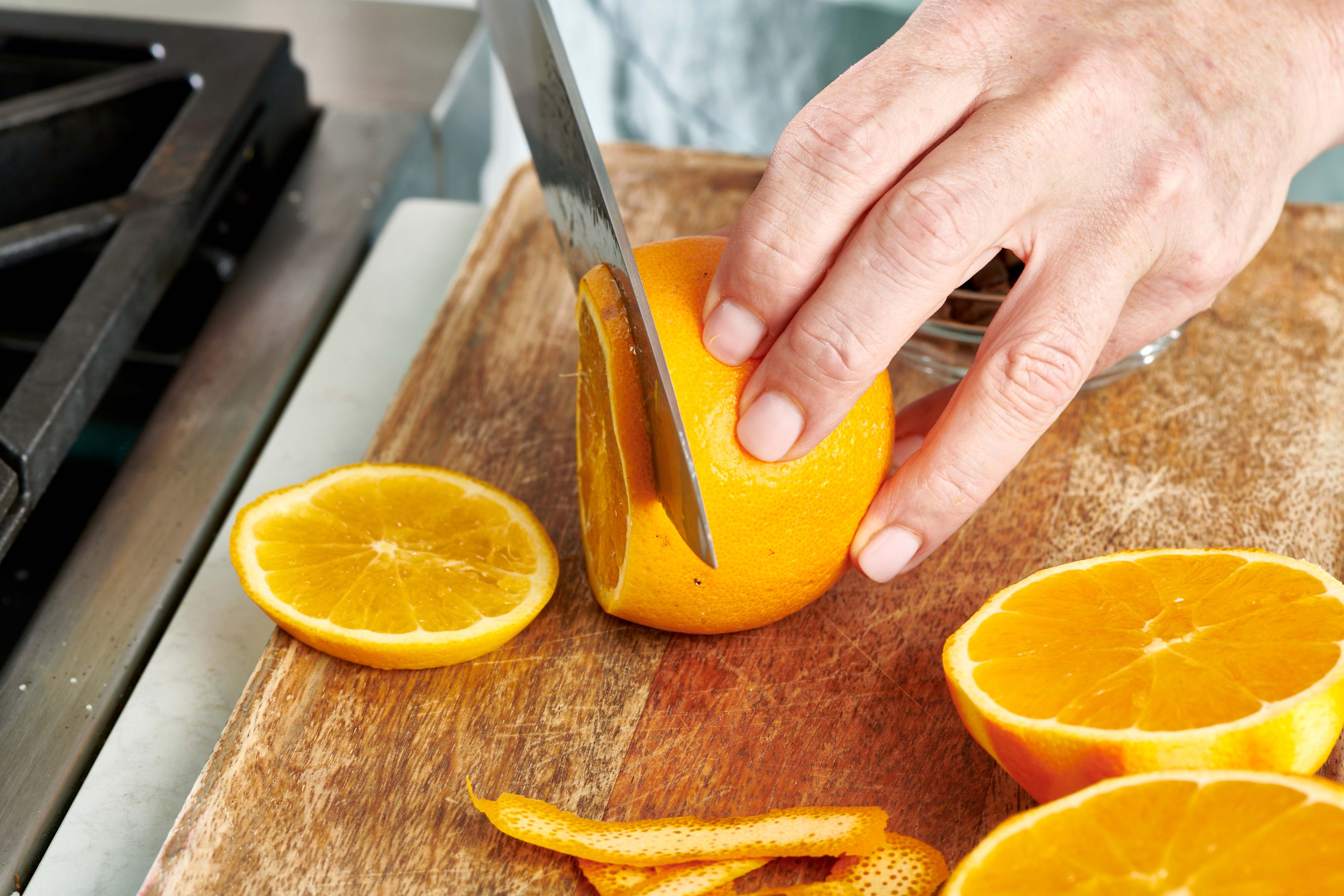 Woman using a knife to thinly slice an orange.