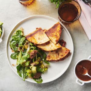 Sliced quesadilla with beef chili and cheese on plate with salad.