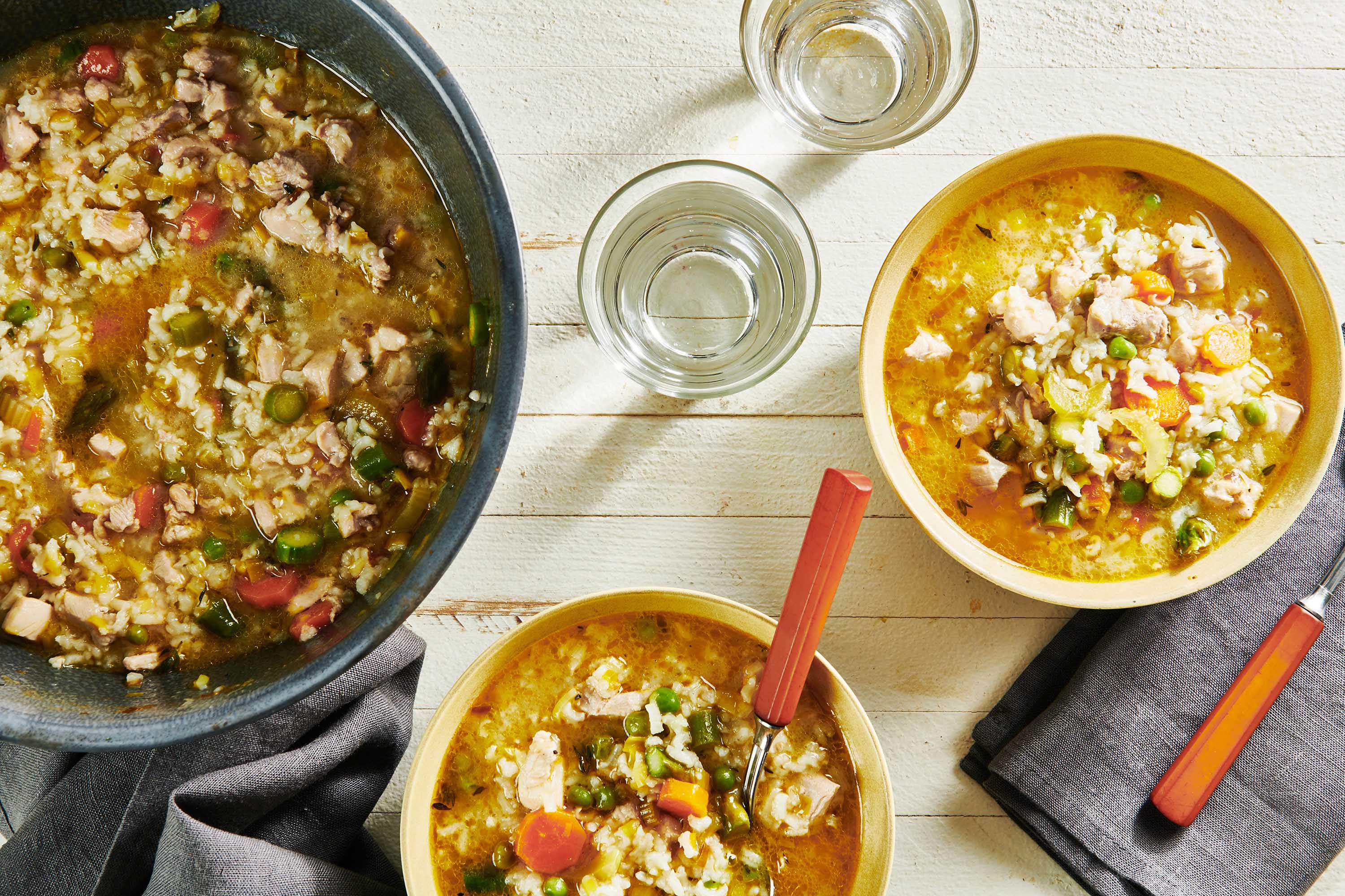 Bowls of Chicken and Rice Soup on a white, wooden table.