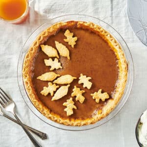 Homemade pumpkin pie with pastry leaf decorations on table.