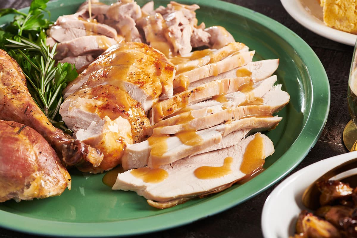 Green platter of Roasted Thanksgiving Turkey with gravy.