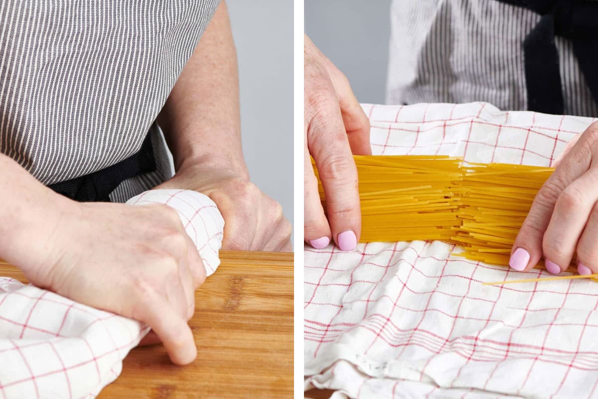 Woman breaking spaghetti in half on a cutting board edge.