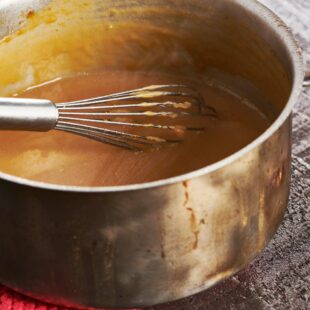 Turkey gravy in pan with whisk.