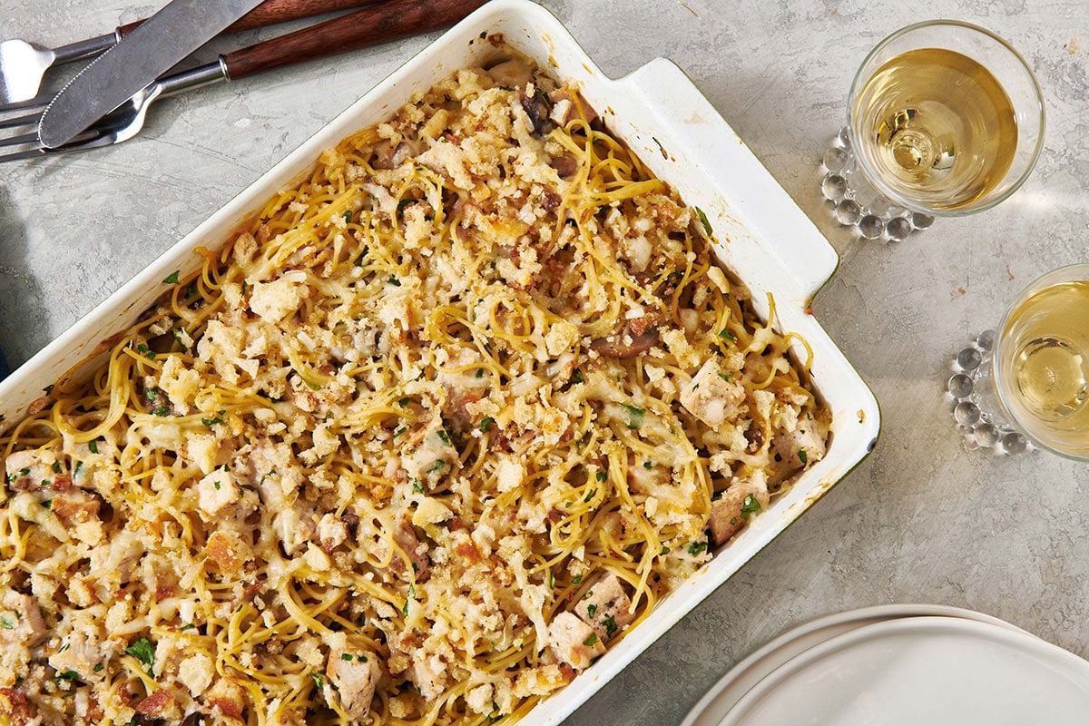 Turkey Tetrazzini in baking dish on table with wine glasses.