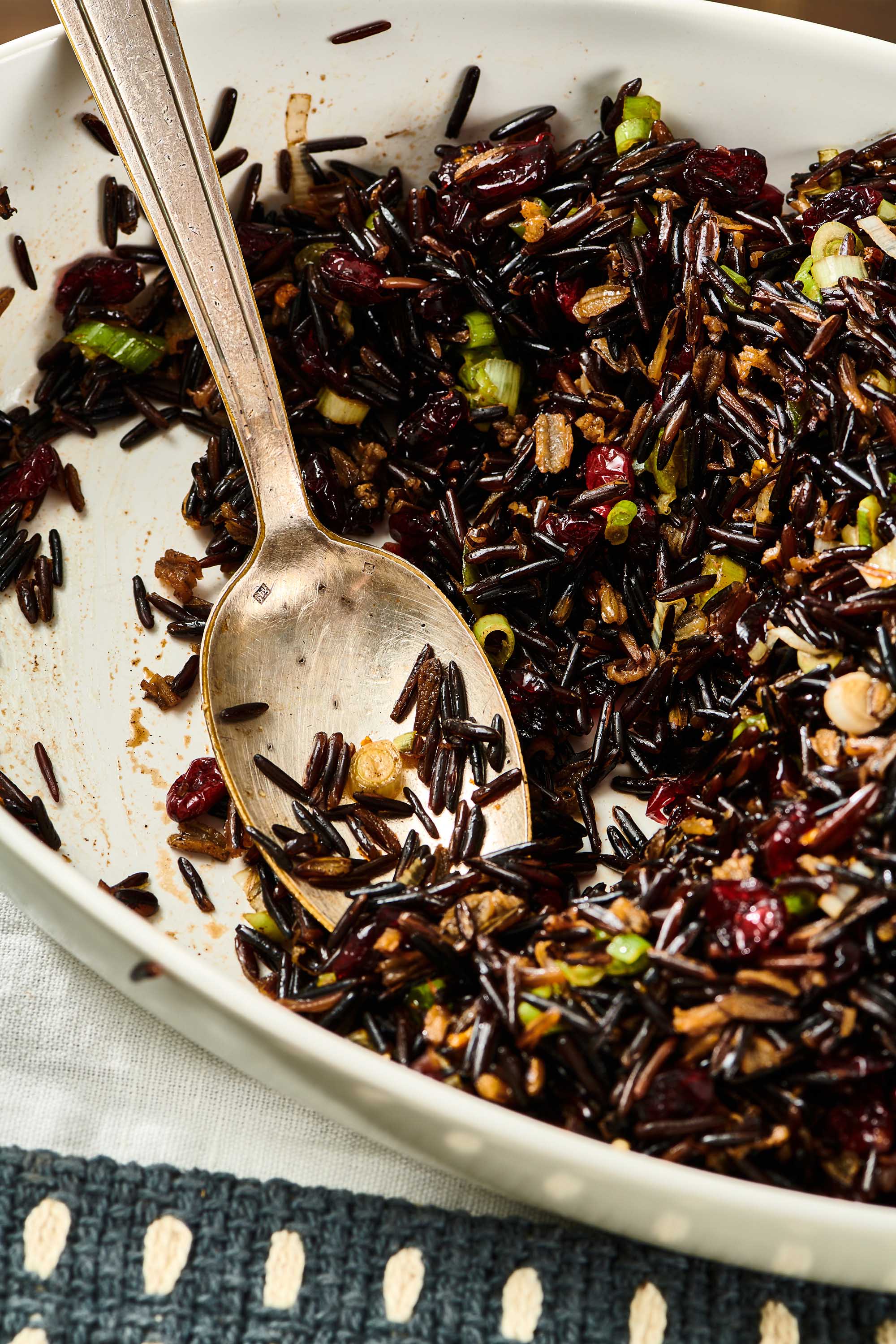 Spoon in a white dish of Wild Rice Salad with Cranberries.