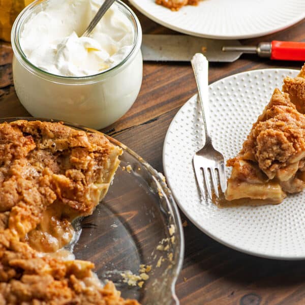 Plates with apple streusel pie on table.