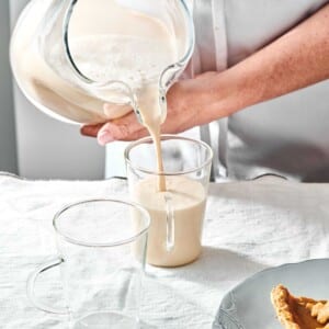 Pitcher pouring Coquito into a glass.