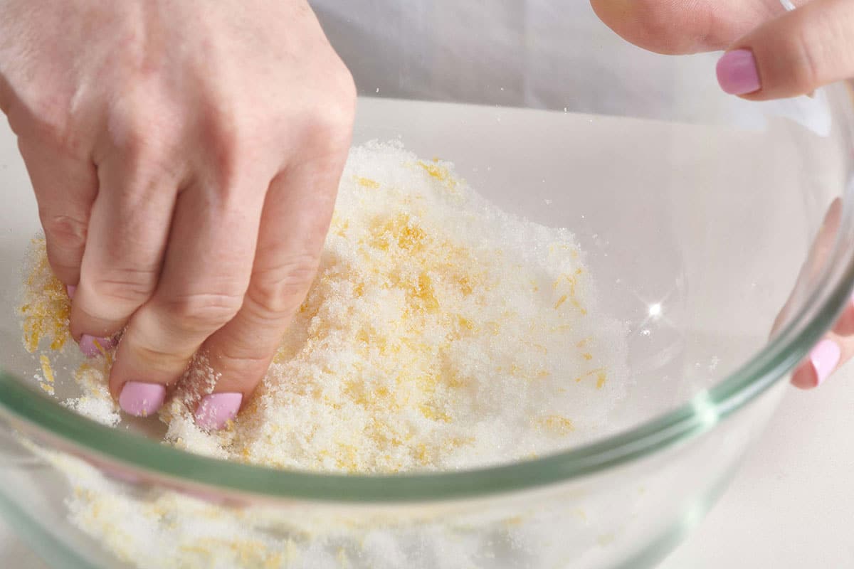 Woman rubbing lemon zest into sugar.