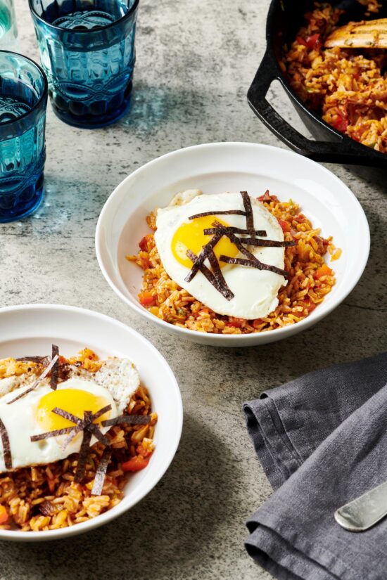 Two bowls of Kimchi Fried Rice topped with eggs.